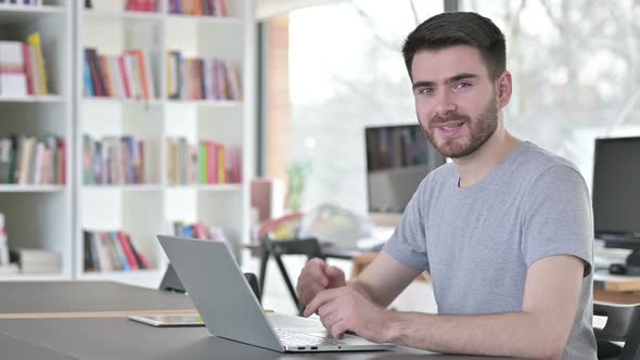 Thumbs Up By Young Man with Laptop in Office