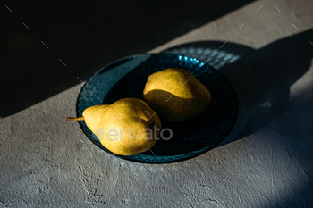Close up one ripe yellow pear in blue glass plate on grey background. Modern minimal still life with / Photodune, Misc