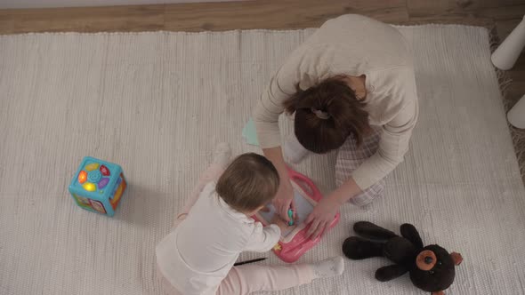 Happy Family Mother Teaching Cute Child Girl Playing on Warm Floor at Home