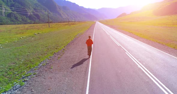 Low Altitude Flight in Front of Sporty Man at Perfect Asphalt Road