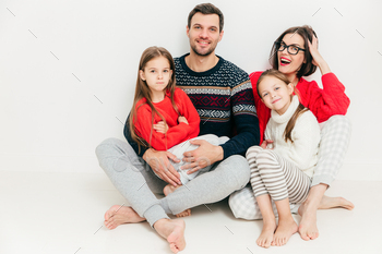 Attractive woman, her husband and two small daughters sit on floor, isolated on white background / Photodune, Misc