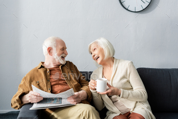 happy senior couple talking while sitting on sofa at home / Photodune, Misc