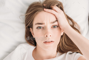 top view of young woman looking at camera while suffering from headache / Photodune, Misc