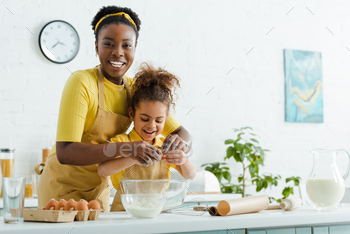 cute african american kid and cheerful mother adding egg in bowl while cooking in kitchen / Photodune, Misc
