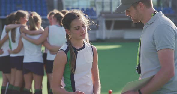 Hockey coach talking with female player on the field