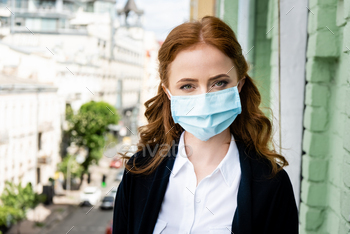 Woman in medical mask looking at camera on balcony / Photodune, Misc