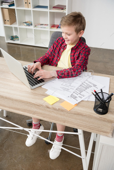 Young schoolboy using fathers laptop at office / Photodune, Misc