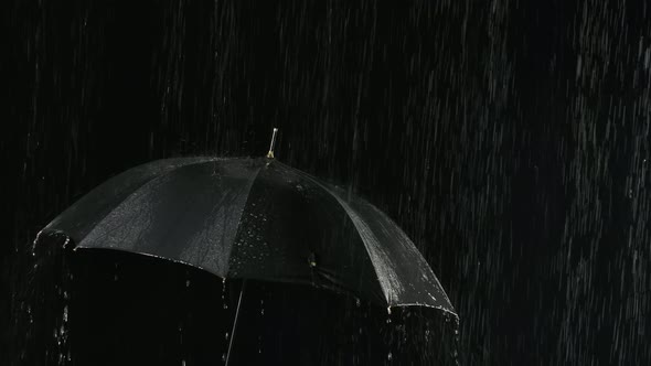 An Open Black Umbrella in the Rain Through Which Streams of Water Flow Down. Filmed Close Up in a