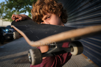 Serious little skater inspecting skateboard / Photodune, Misc