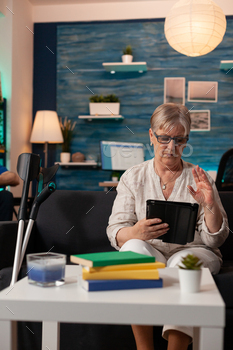 Retired woman waving at video call camera on tablet / Photodune, Misc