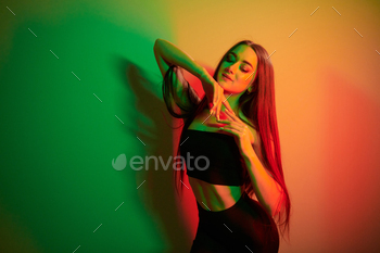 Against wall. Fashionable young woman standing in the studio with neon light / Photodune, Misc
