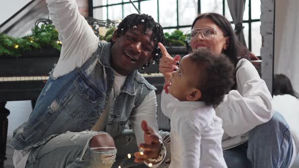 Charming Curlyhaired Mixedrace Baby Boy Amazed By Christmas Lights Shown to Him By His Multiracial