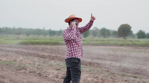 Asian farmer taking a call on smartphone. farmer complaining on a phone call among farm