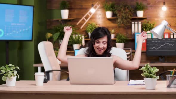 Successful Young Businesswoman Dances in Front of the Laptop