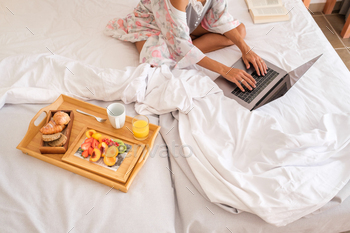 Woman with laptop and breakfast in bed / Photodune, Misc