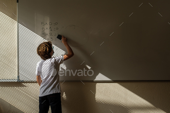  mathematical examples while standing near whiteboard in classroom during lesson