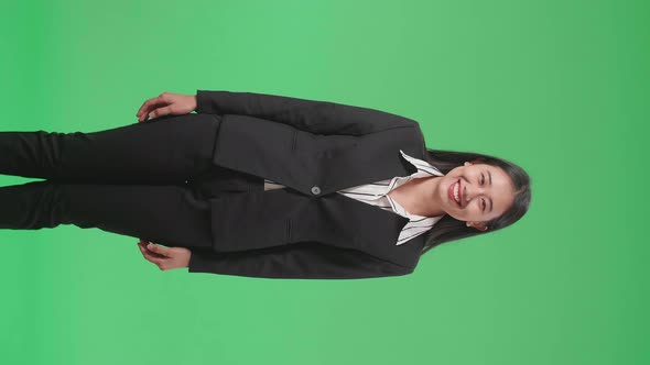 An Asian Business Woman Warmly Smiling On Green Screen Background In The Studio