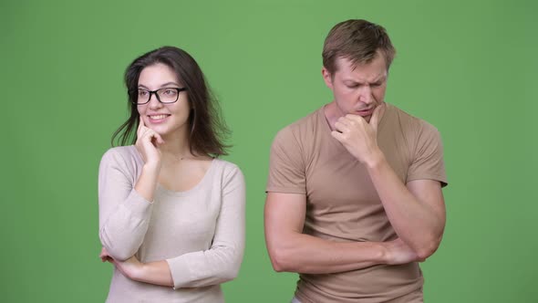 Young Couple Thinking Together Against Green Background