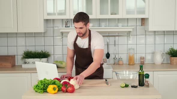 Man Looking at Vegan Salad Recipe Using Laptop