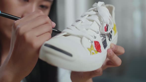 Close Up Of Asian Female Footwear Designer Putting Coloured Unique Patterns On Sneakers