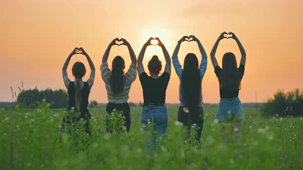 Five Girls Make a Heart Shape From Their Hands at Sunset