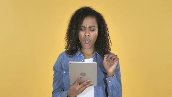 African Girl in Shock While Using Tablet Isolated on Yellow Background