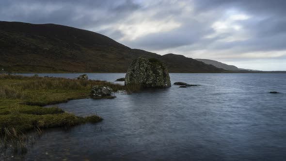 Time Lapse on a remote lake shore on dramatic cloudy day in Ireland.