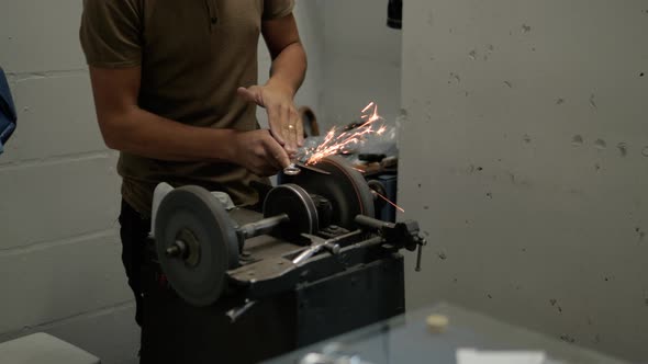 Closeup Shot of a Man's Hands Sharpening a Scissors