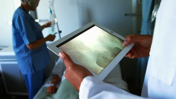 Mixed race male doktor working in a medical centre, using a tablet and  looking at a scan, with his
