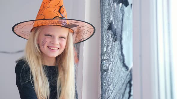 Laughing Happy Blonde Girl in Witch Costume Preparing for Halloween at Home
