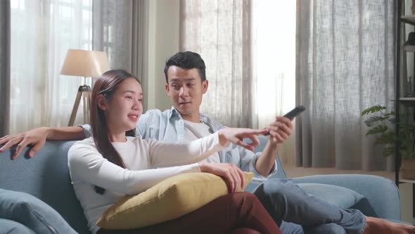 Young Asian Couple Relaxing And Watching Tv At Home