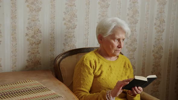 Senior Caucasian Woman Holding the Bible and Pondering Medium Shot Living Room Religion and