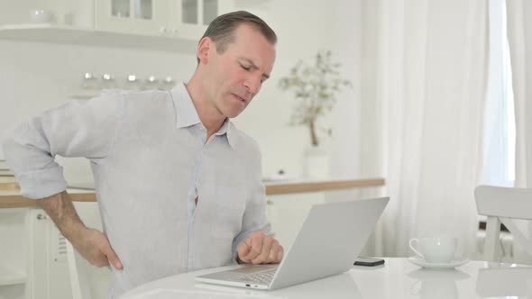 Middle Aged Man with Laptop Having Back Pain at Home