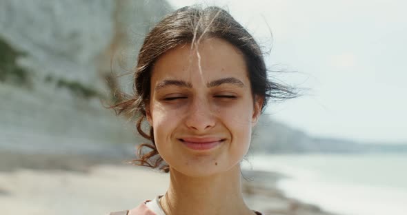 A Young Woman Walks Along a Pebbly Beach Past Sheer Chalk Cliffs