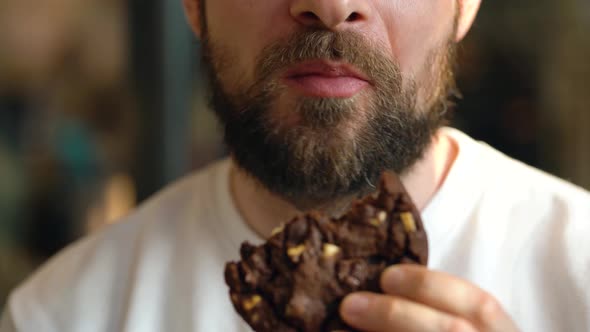 Man Eats a Chocolate Chip Cookies in a Cafe
