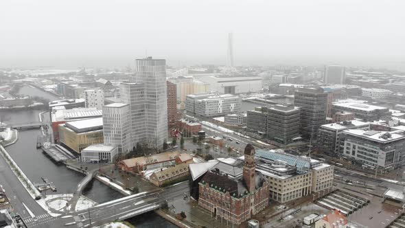 Drone flying forward over Malmö while it is snowing.  Clarion hotel, turning torso, Malmo university