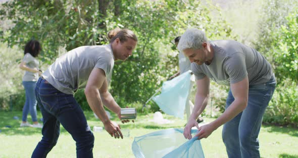 Two caucasian young male volunteers collecting plastic material in a bag and high fiving each other