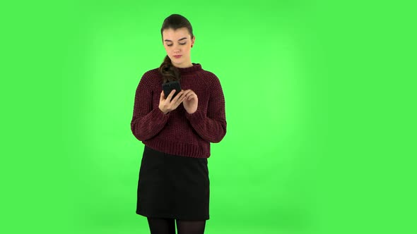 Young Woman Texting on Her Phone. Green Screen