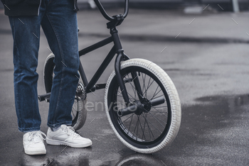 cropped shot of boy standing with bmx bicycle on street