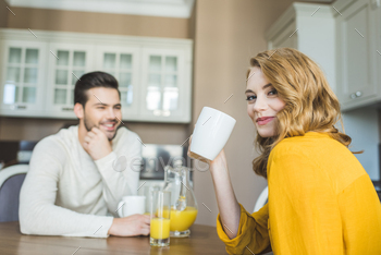 Lovely couple drinking coffee in kitchen at home / Photodune, Misc