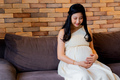 Happy Asian pregnant woman on couch - PhotoDune Item for Sale
