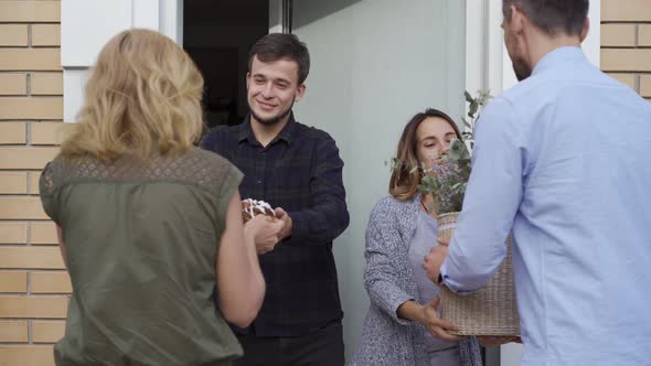 Young Happy Family Standing at Doors and Waiting for Their Neighbours To Present Them