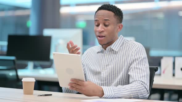 African Businessman Making Video Call on Tablet in Office