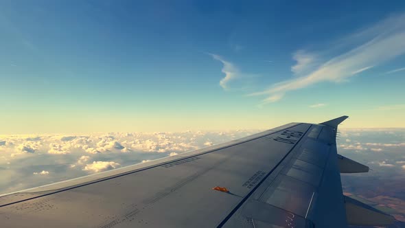 Wing of Passenger Airplane Flying High Above Fluffy Clouds