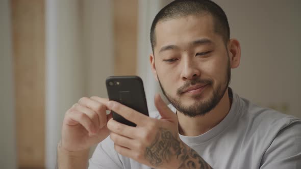 Tattoed Man Showing a Dislike Emotion with a Smart Phone in Hands