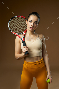  expression while holding tennis equipment. Isolated on beige background