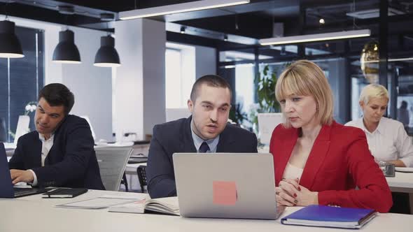 Man Helping Woman Working with Laptop Pc in Office