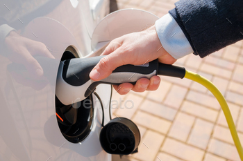 Top view of man hand inserting the power cable supply plugged into the electric car for recharging / Photodune, Misc