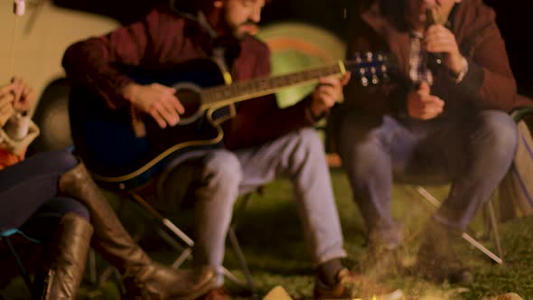 Camping Fire Burning While Man's Singing on Guitar