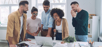 Group of happy young people in smart casual wear looking at laptop and gesturing / Photodune, Misc